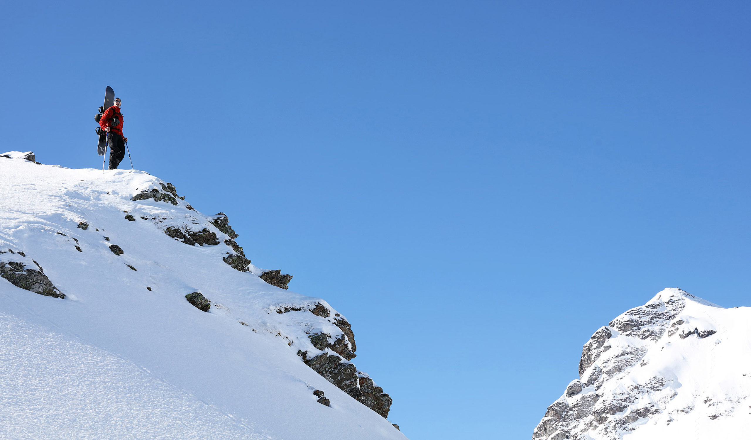 Reiten im Pulverschnee an einem schönen Tag in den Schweizer Alpen. Freeriden ist in der Schweiz sowohl bei Snowboardern als auch bei Skifahrern beliebt. Es gibt Zeiten im Winter, in denen die Berge vom Abenteuer sprechen. Der Wind weht warm aus dem Süden, um die kommenden Veränderungen anzukündigen, die Sonne verweilt noch ein wenig länger, aber dennoch schenkt der Himmel in seiner sanften Liebenswürdigkeit diesen Ländern einen frischen Spritzer unberührten Pulvers. Dies sind die Tage des Zuckers.